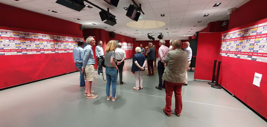 Stadiontour: Besuchergruppe in einem Raum mit Sponsorenwand des SC Freiburg